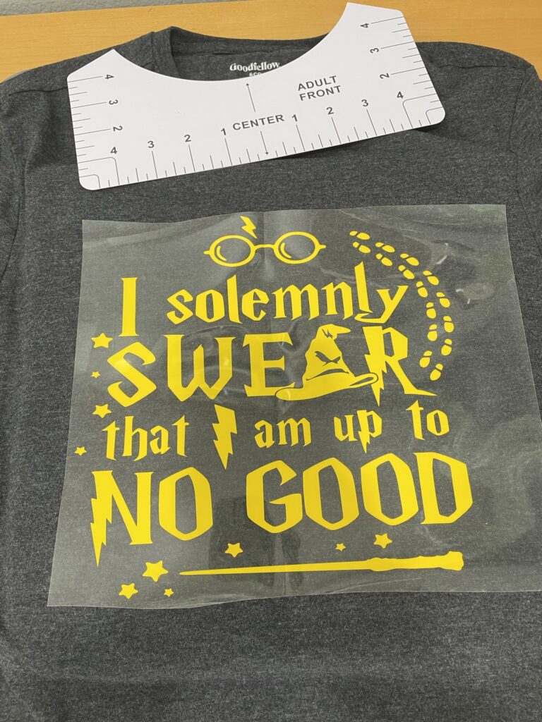 Gray t-shirt with a shirt ruler near the collar and a yellow design that says "I solemnly swear that I am up to no good"