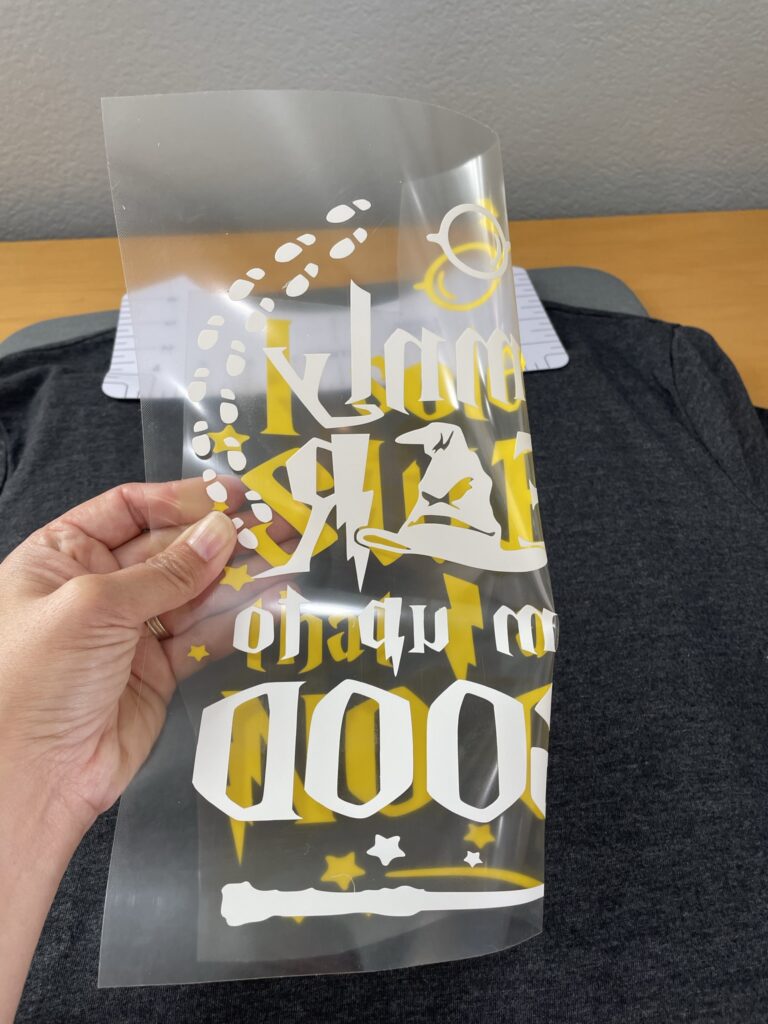 Piece of transfer sheet with iron on design folded in half with a shirt in the background