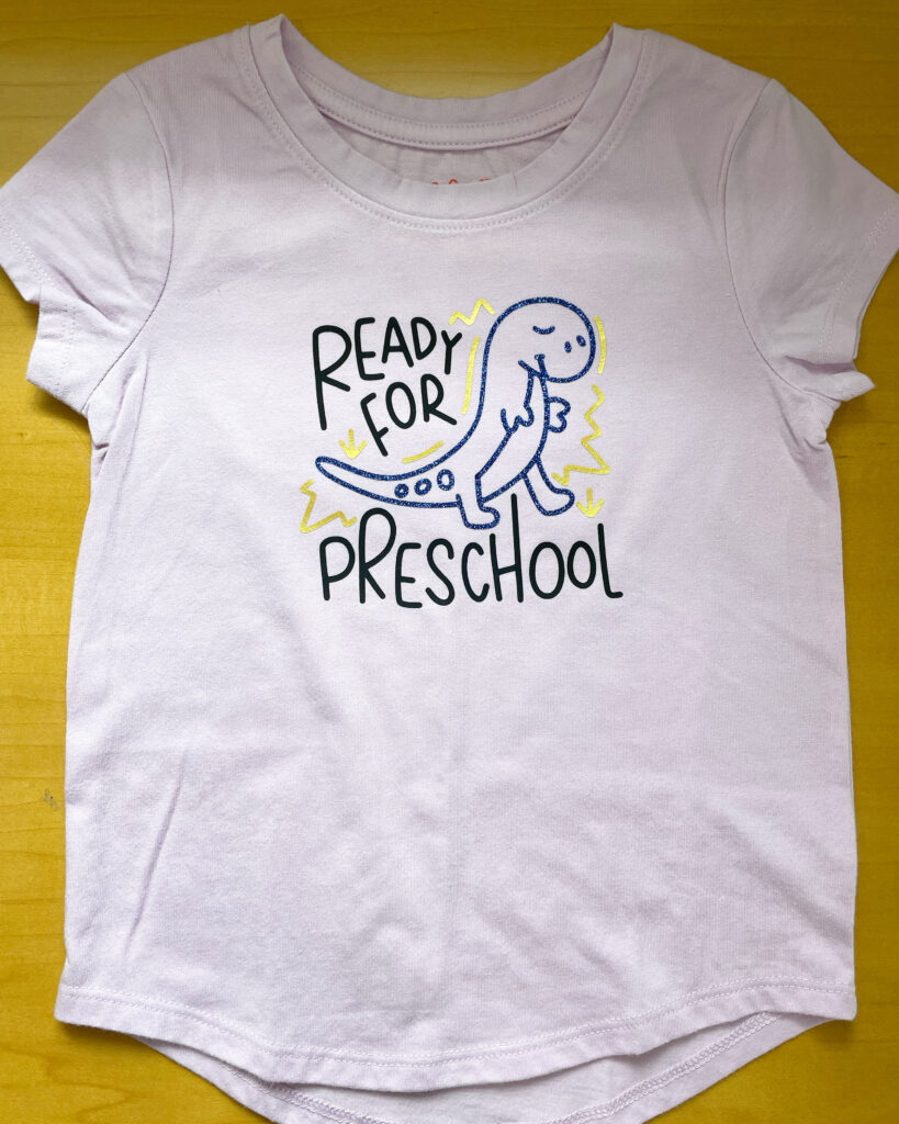 Light lavender shirt that says READY FOR PRESCHOOL with a cartoon T-rex